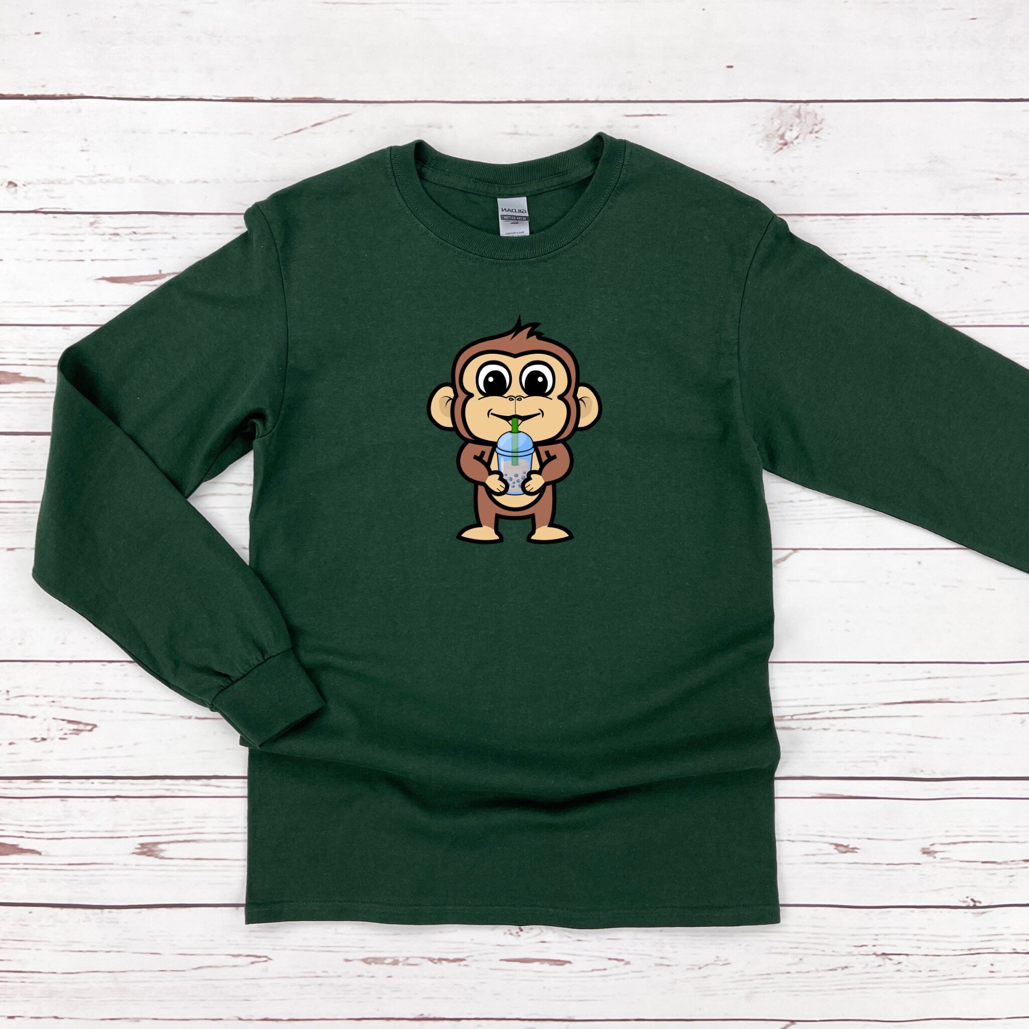 a green shirt with a cartoon monkey holding a ball