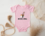 a pink baby bodysuit with a sushi on a roll on it