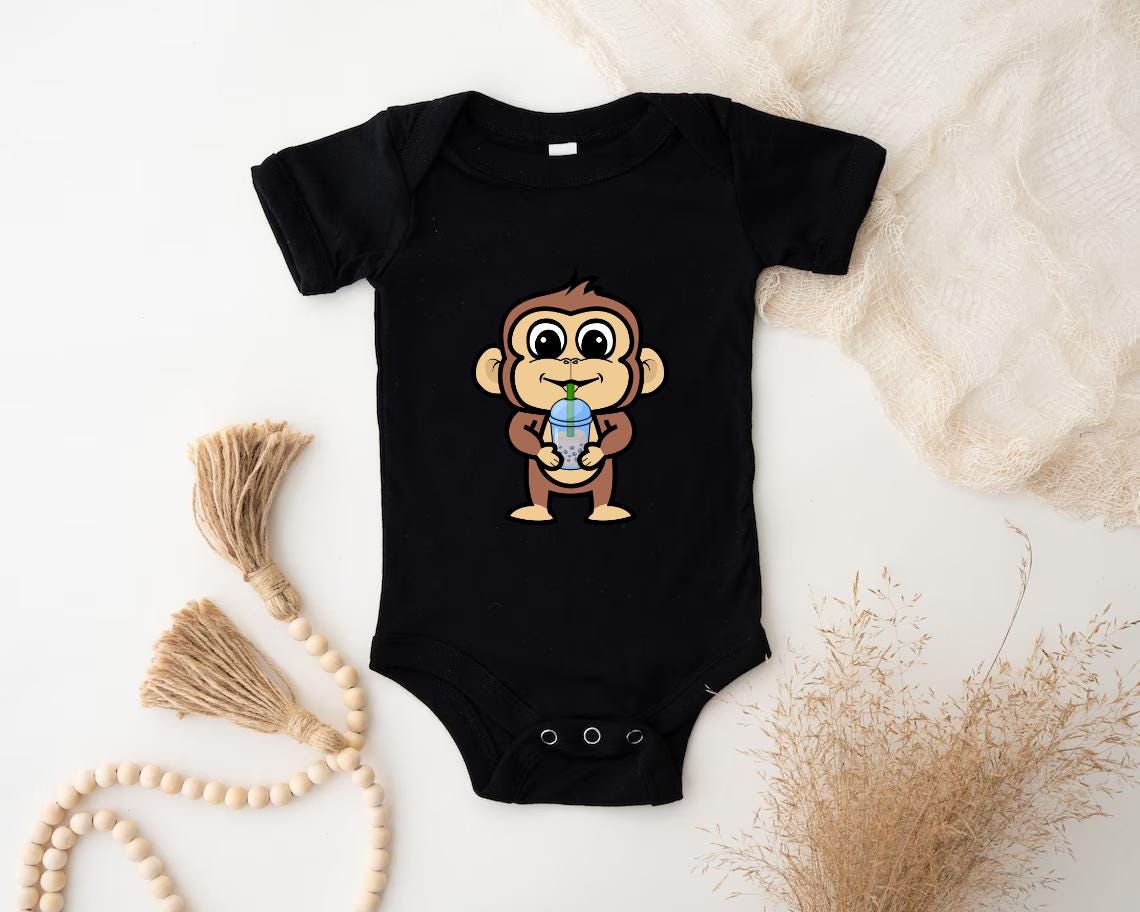 a black baby bodysuit with a cartoon monkey holding a blue ball