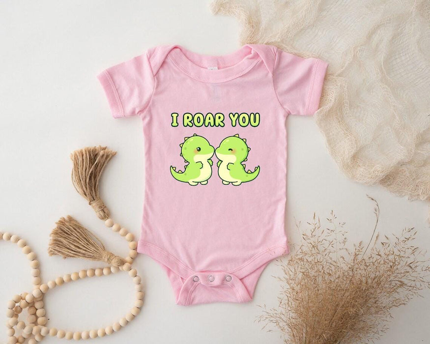 a pink baby bodysuit with two green birds on it