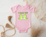a pink baby bodysuit with two green birds on it