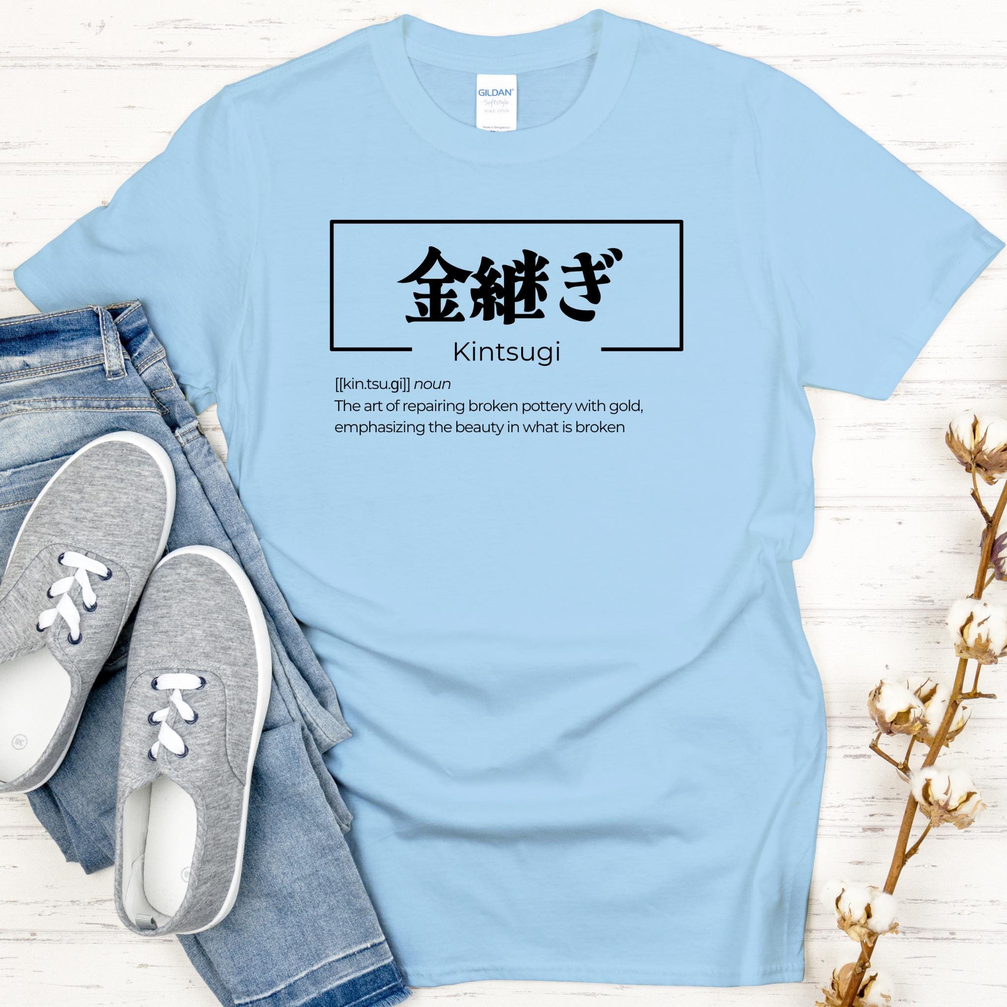 a t - shirt that says kintsugi on it next to a pair of