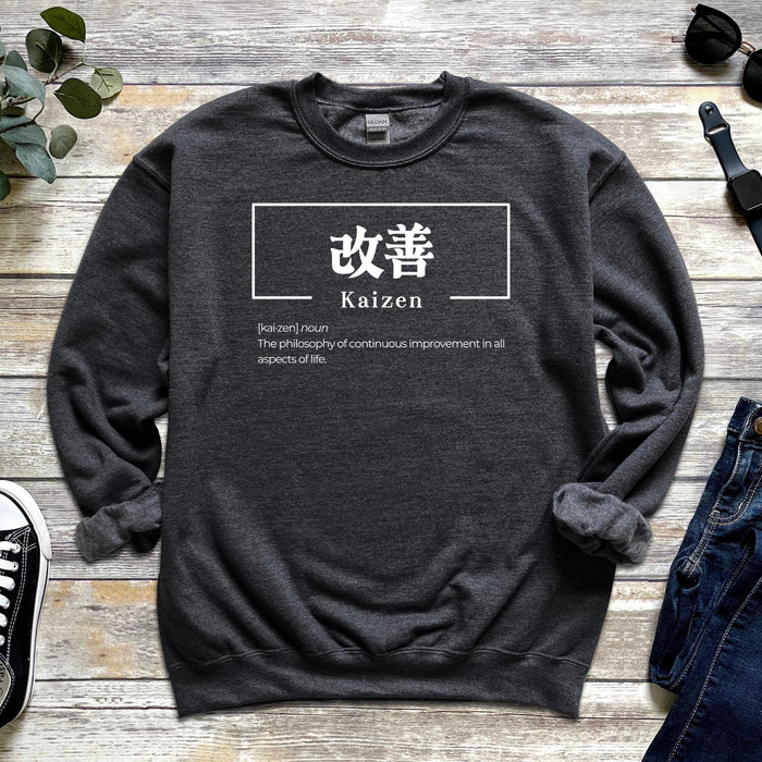 a sweater with the words kaizen on it next to a pair of jeans