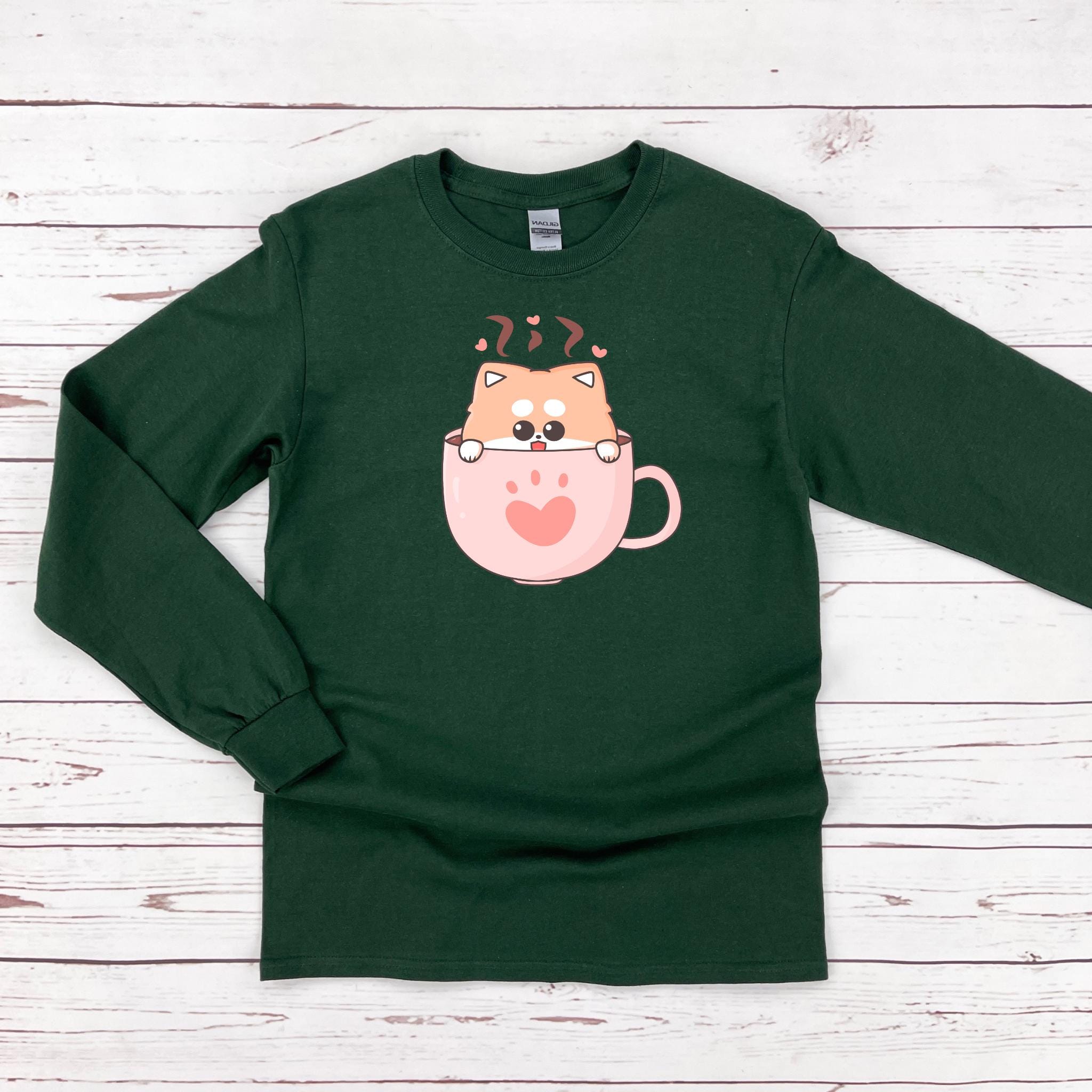 a green shirt with a cat in a cup on it