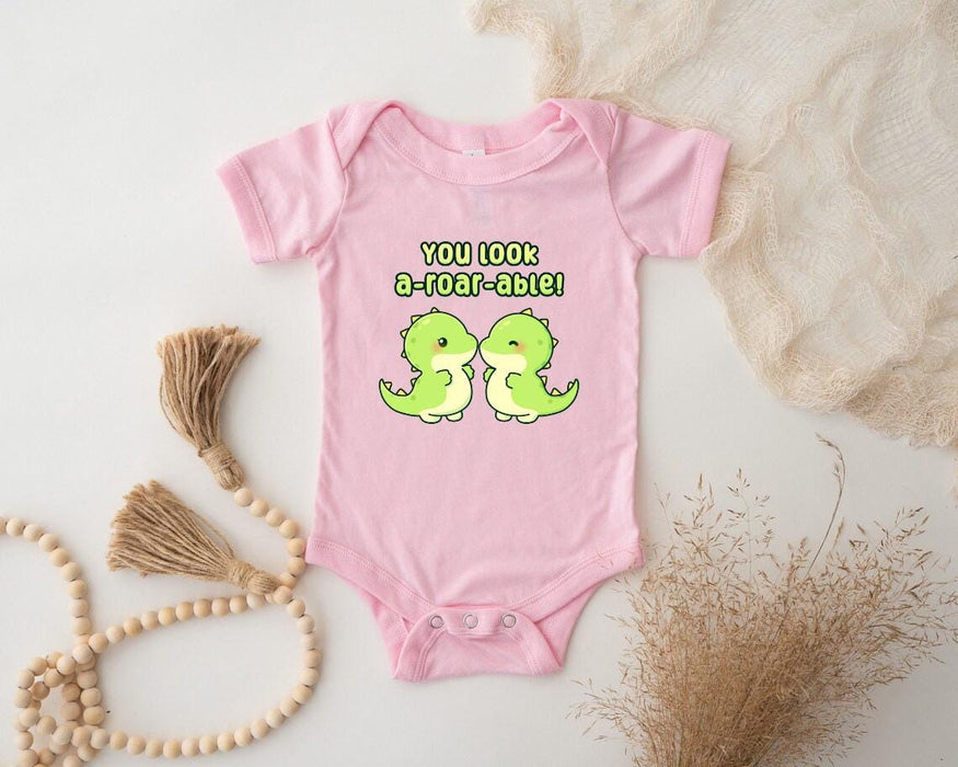 a pink baby bodysuit with two green birds on it