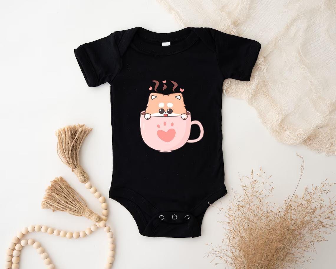 a baby bodysuit with a cat in a cup on it