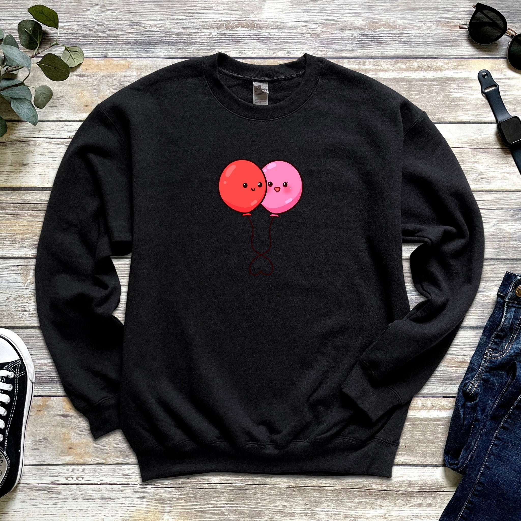 a black sweater with two red balloons on it