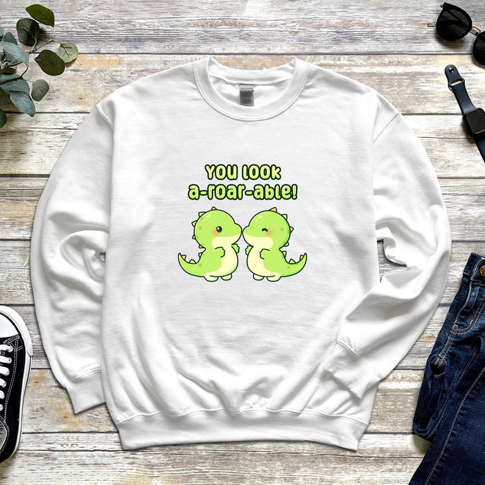 a white sweatshirt with two green dinosaurs on it