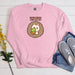 a pink sweatshirt with an image of a hedge holding a ball