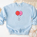 a blue sweatshirt with two balloons drawn on it