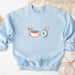 a blue sweatshirt with a picture of coffee and donuts on it