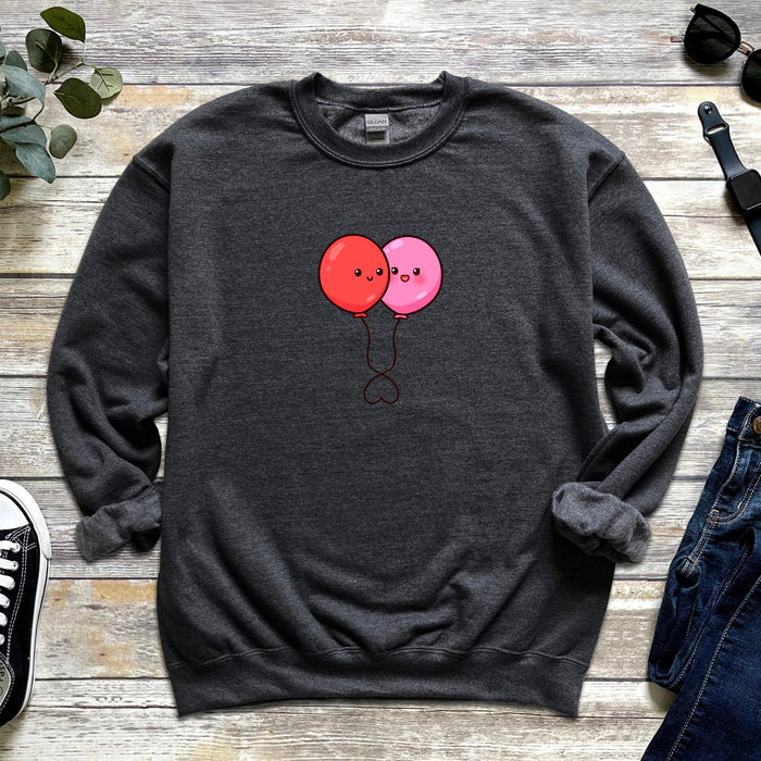 a sweater with two balloons on it next to a pair of jeans