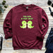 a red sweatshirt with two green dinosaurs on it