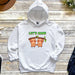 a white hoodie with two slots hanging from a tree