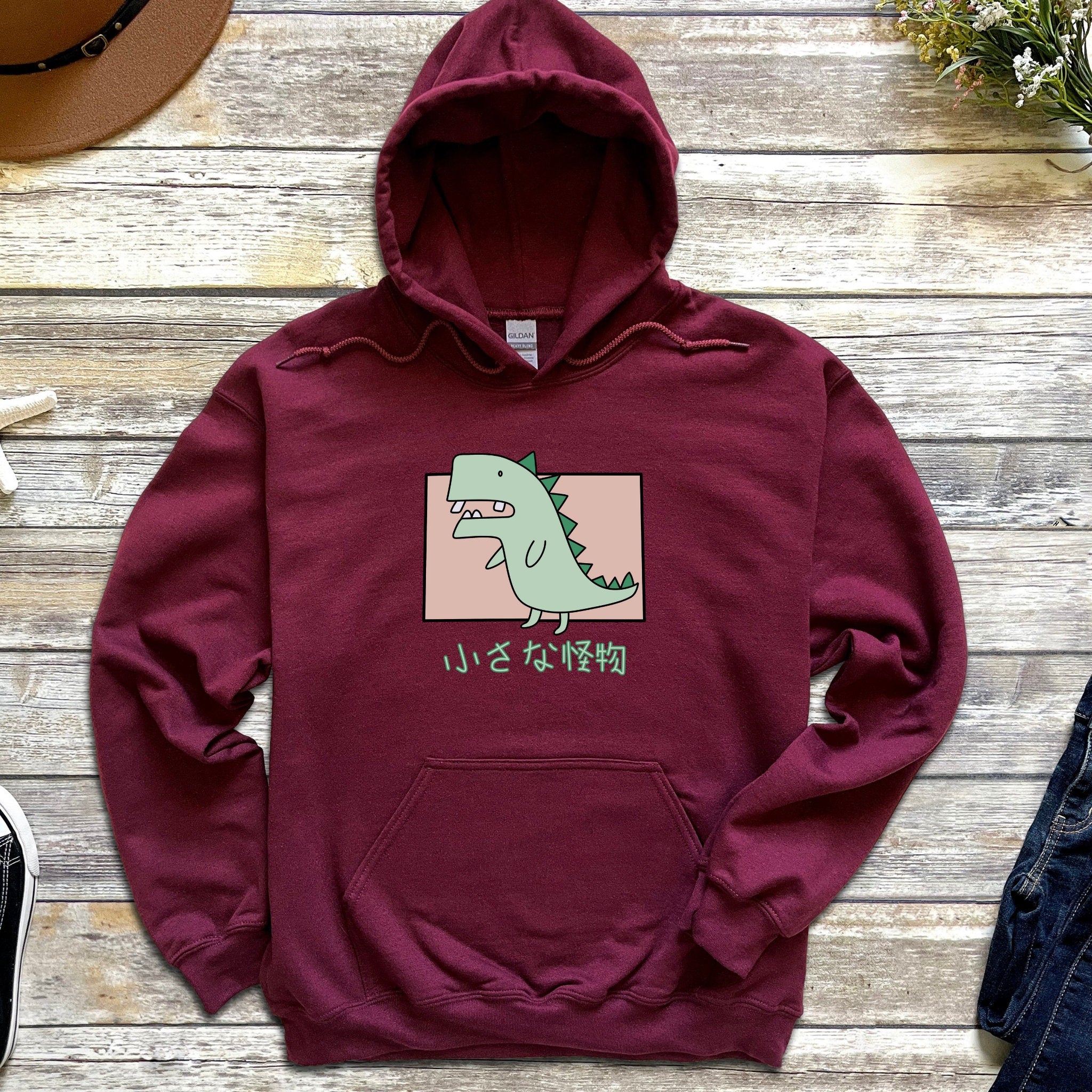 a red hoodie with a green dinosaur on it