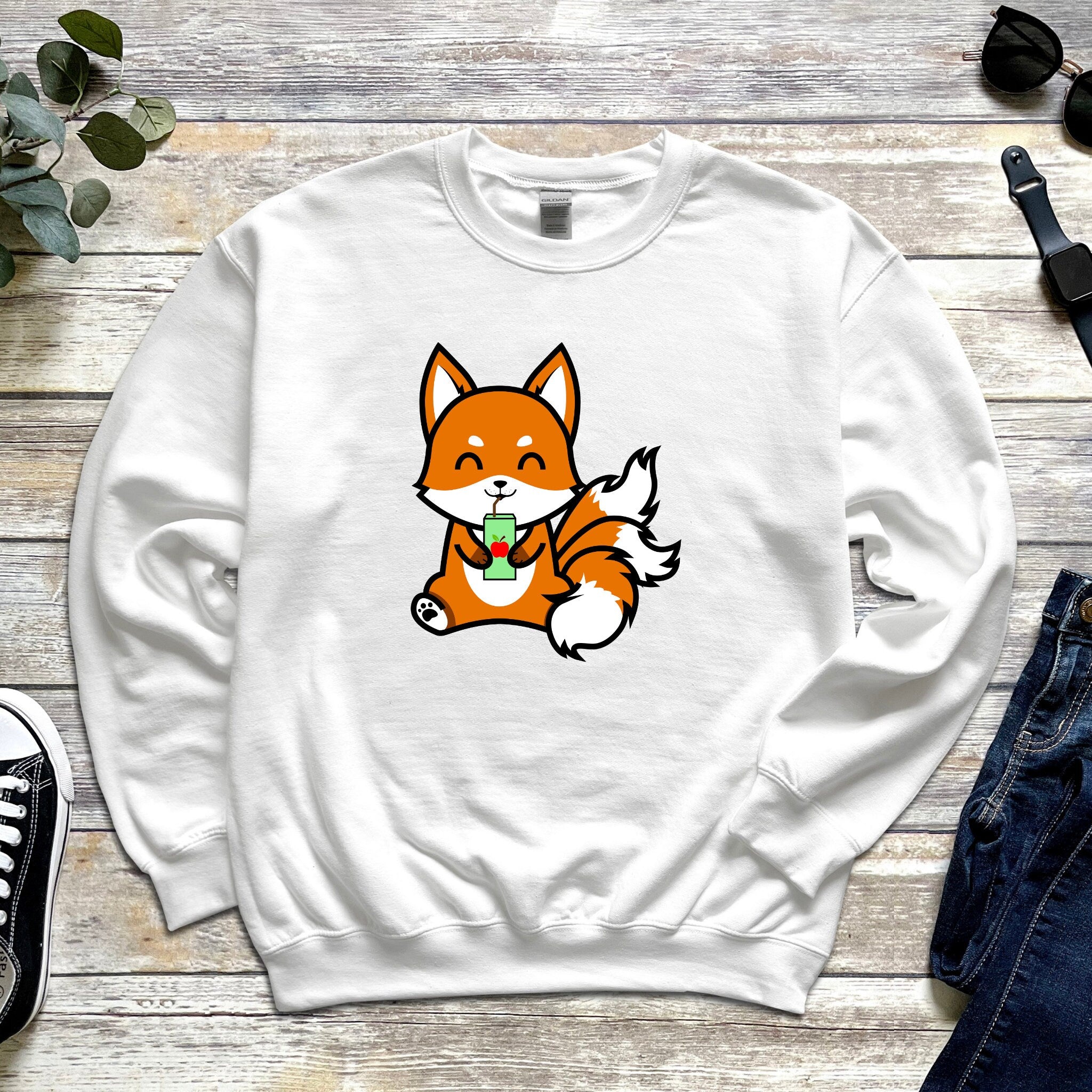 a white sweatshirt with a cartoon fox eating a piece of broccoli