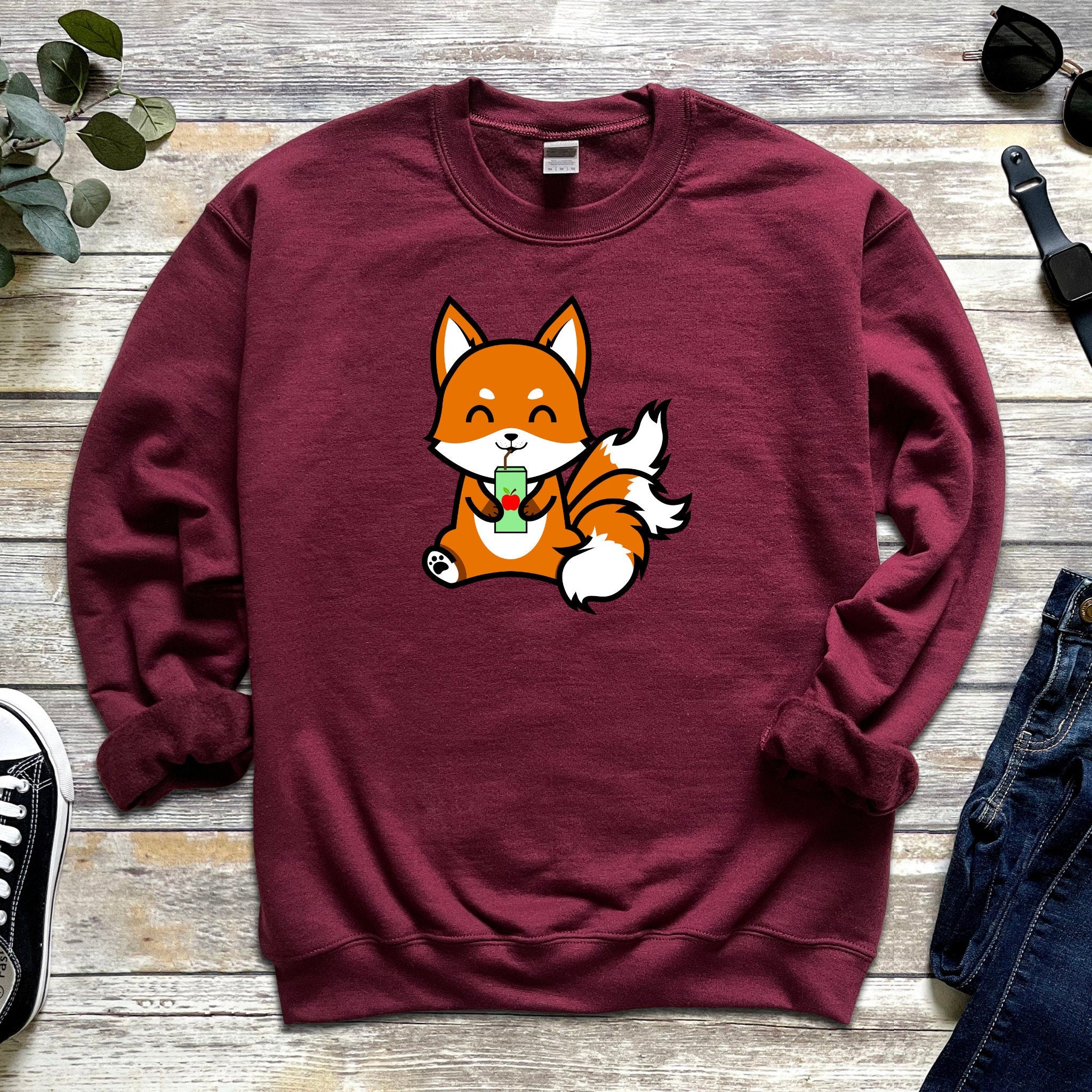a red sweatshirt with a cartoon fox eating an apple