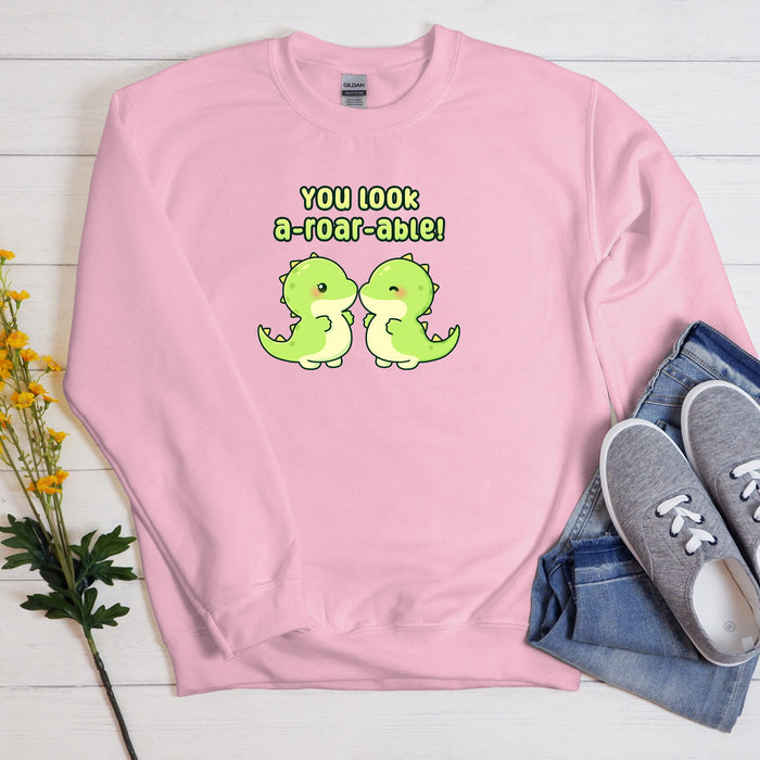 a pink sweatshirt with two green dinosaurs on it