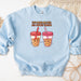 a blue sweatshirt with two cups of cookies and a straw