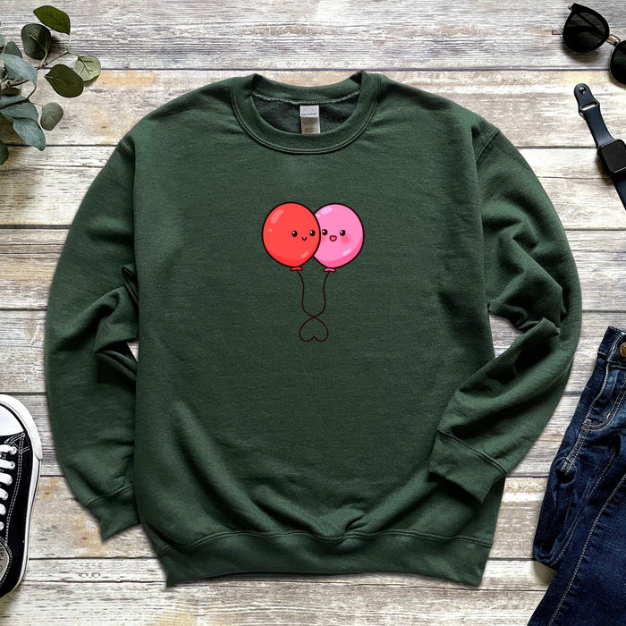 a green sweatshirt with two pink balloons on it