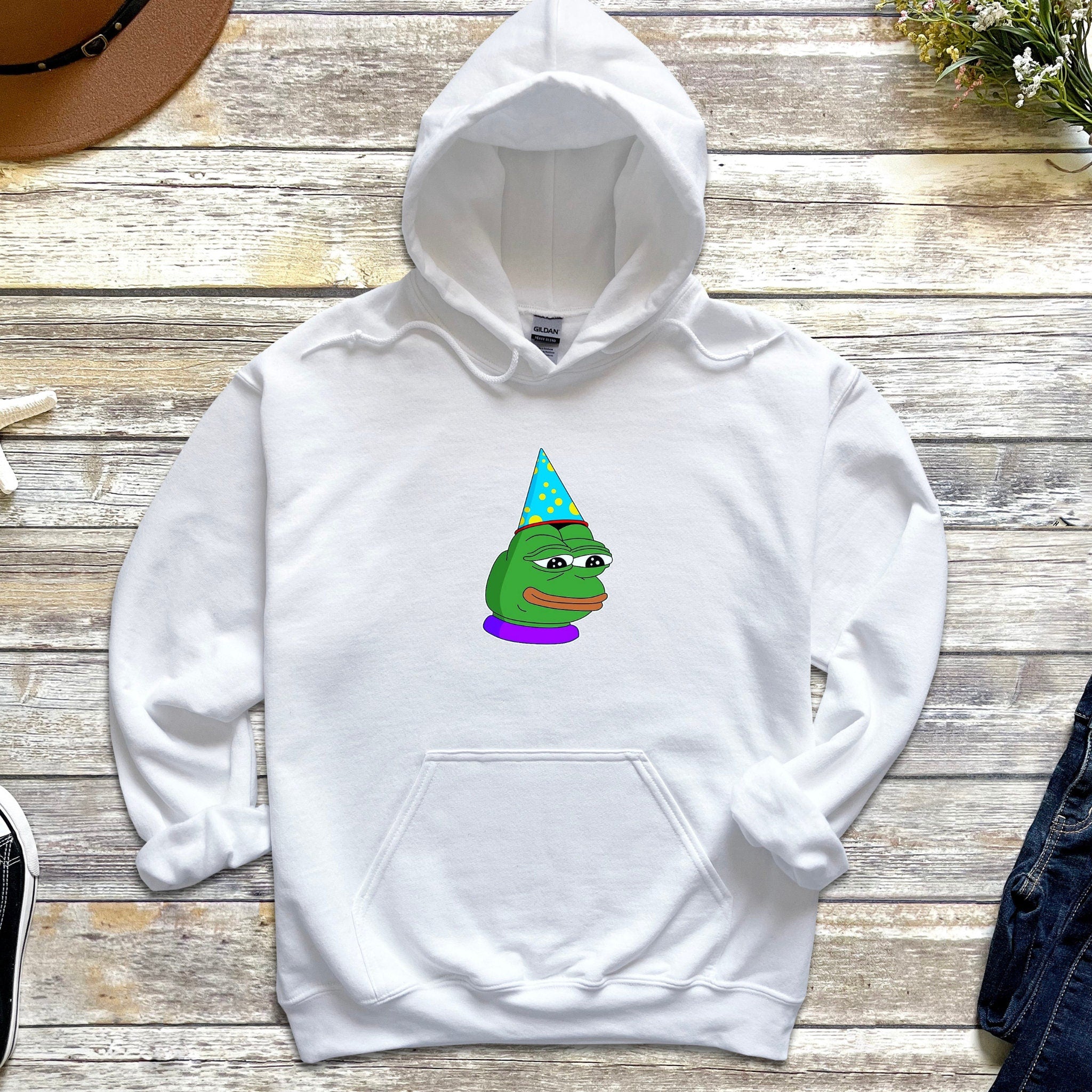a white hoodie with a cartoon of a frog wearing a party hat
