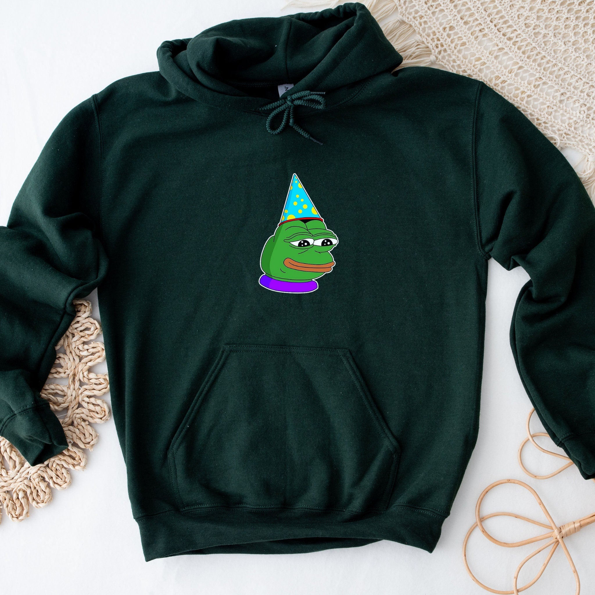 a green hoodie with a frog wearing a party hat