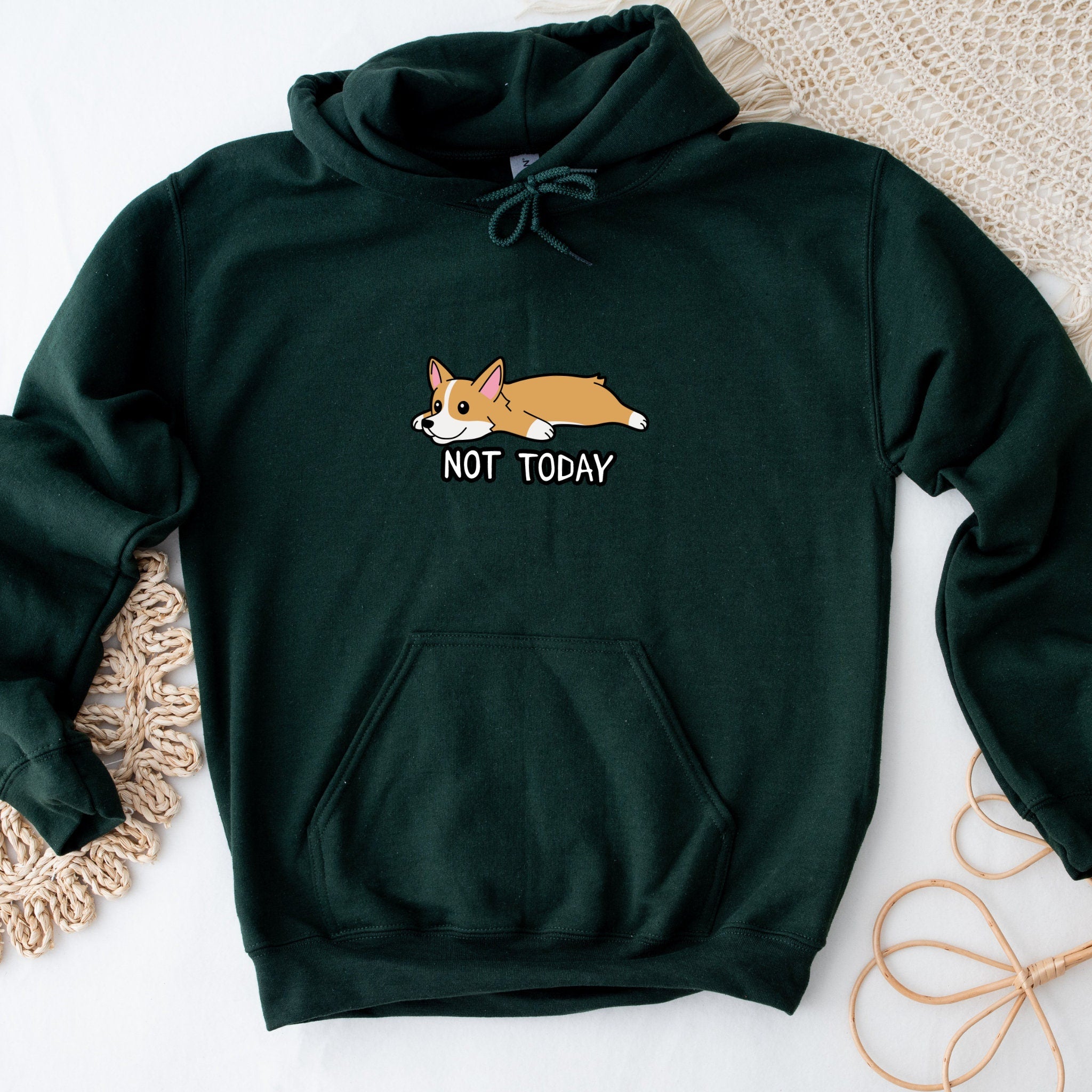 a green sweatshirt with a picture of a corgi sleeping on it